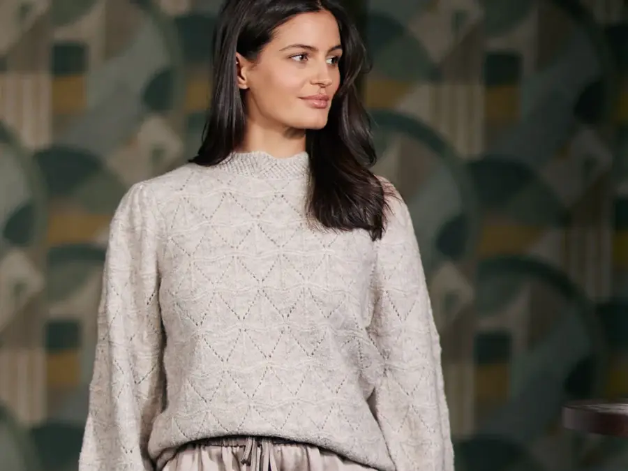 Bilde av en kvinne i en hvit/grå strikket genser som ser til siden