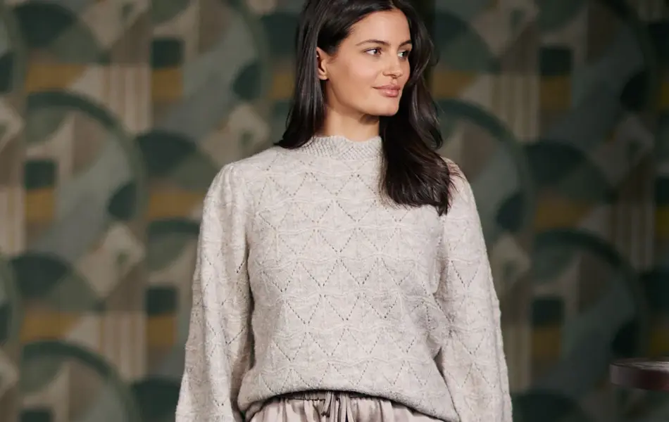 Bilde av en kvinne i en hvit/grå strikket genser som ser til siden