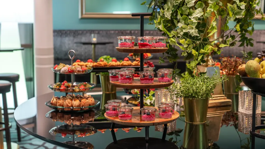 Pausebuffet med diverse fargerik mat på etasjefat, og grønne planter.