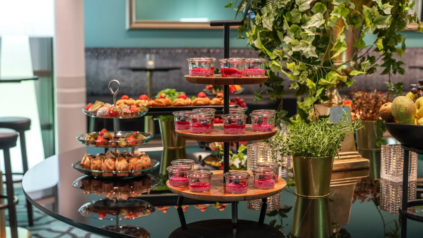 Pausebuffet med diverse fargerik mat på etasjefat, og grønne planter.