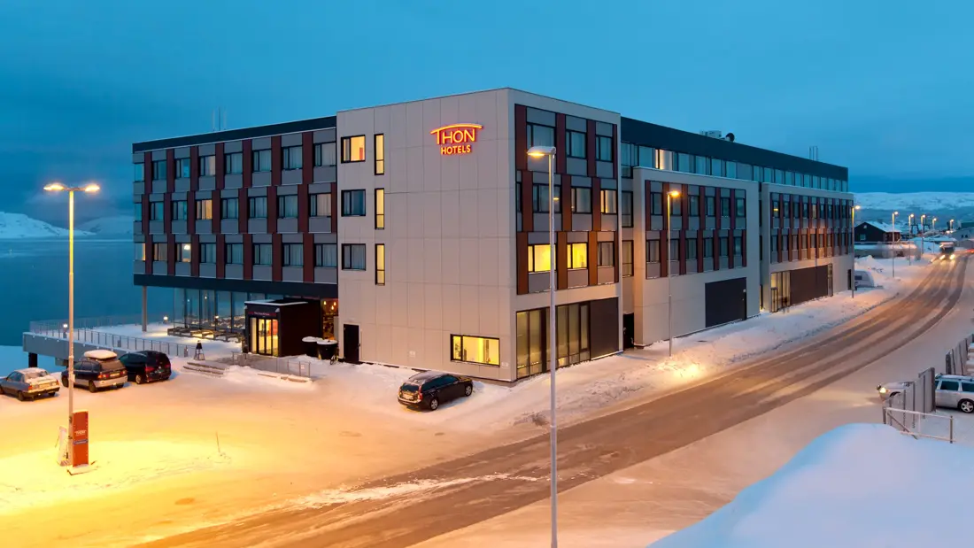 Fasade av bygningen til Thon Hotel Kirkenes ved kaia i Kirkenes sentrum på vinteren på kvelden