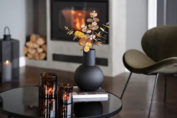 Rundt bord med sort vase og telysholdere i brunt glass