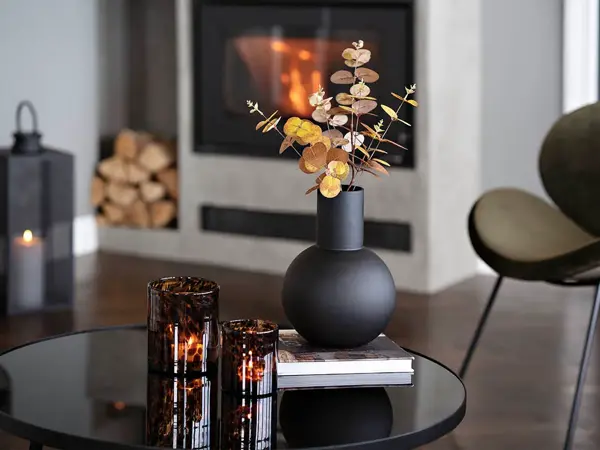 Rundt bord med sort vase og telysholdere i brunt glass