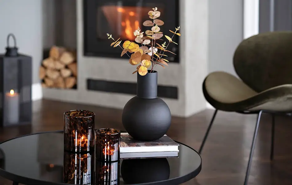 Rundt bord med sort vase og telysholdere i brunt glass