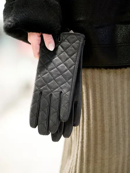 Hånd holder sorte skinnhansker