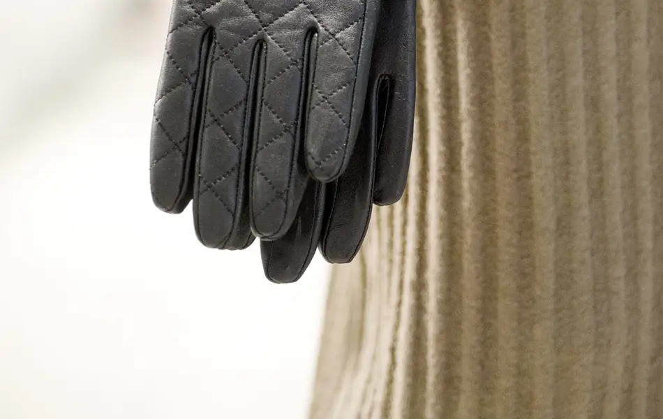 Hånd holder sorte skinnhansker