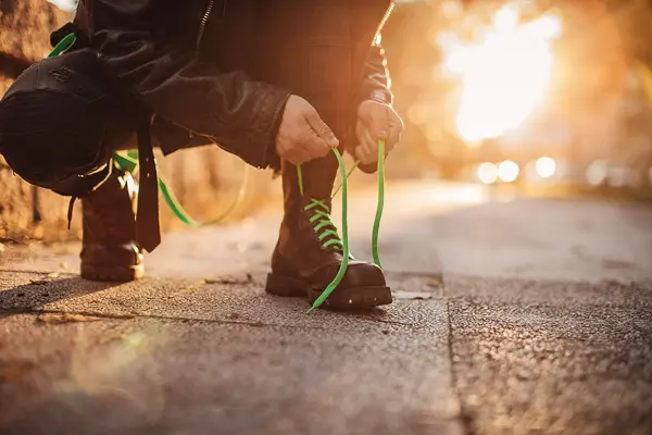 Nærbilde av mann som knytter lisser på combat boots 
