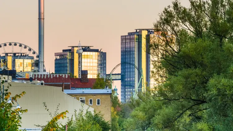 To kajakkpadlere på elven i Gøteborg. I bakgrunnen ses skyskrapere, pariserhjul og utsiktstårnet AtmosFear/Lisebergtårnet