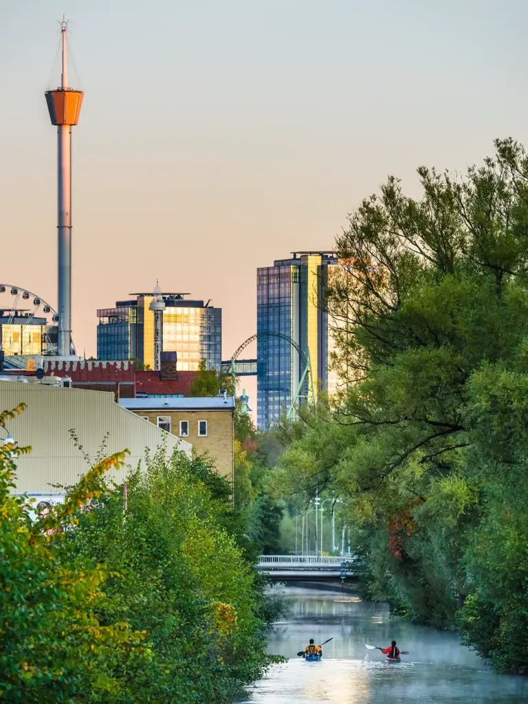 To kajakkpadlere på elven i Gøteborg. I bakgrunnen ses skyskrapere, pariserhjul og utsiktstårnet AtmosFear/Lisebergtårnet