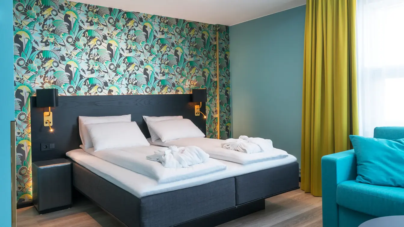 Superior room med tapet, gardiner, turkis lenestol og dobbeltseng