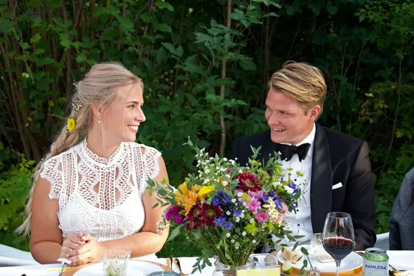 Nygift brudepar sitter ved bordet i en hage