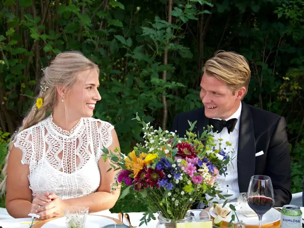 Nygift brudepar sitter ved bordet i en hage