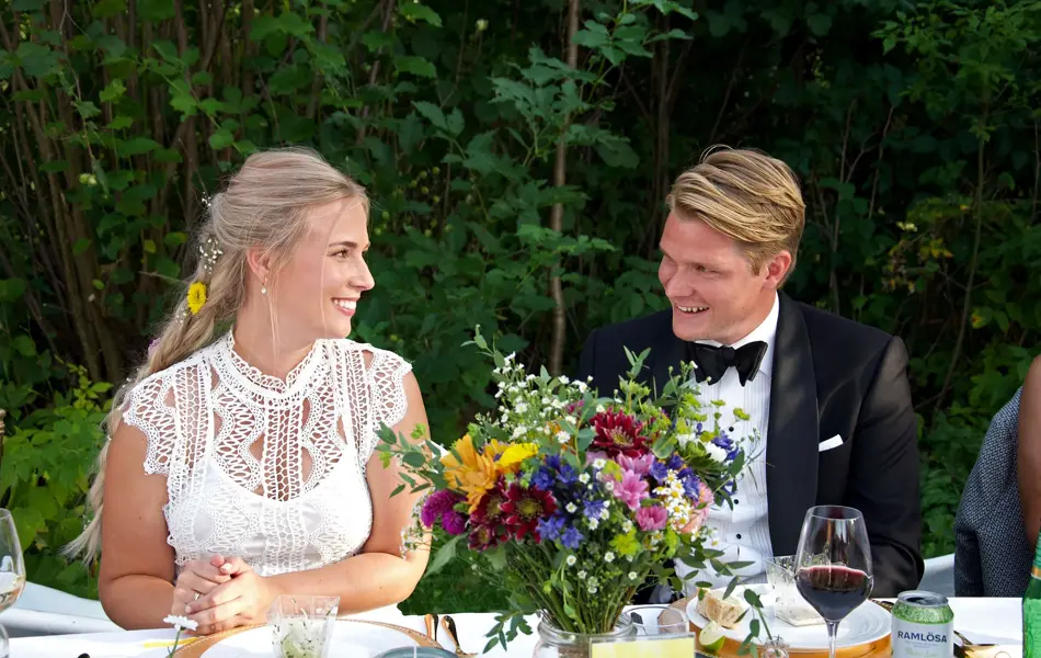Nygift brudepar sitter ved bordet i en hage