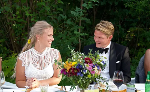 Nygift brudepar sitter ved bordet i en hage