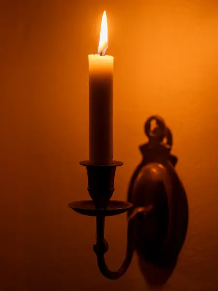 Nærbilde av vegglysestake med tent stearinlys