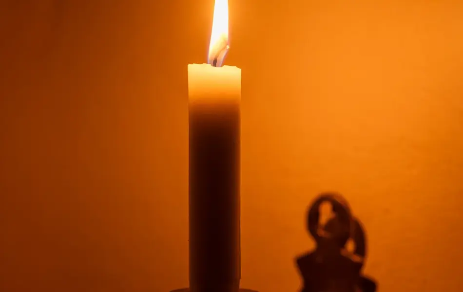 Nærbilde av vegglysestake med tent stearinlys