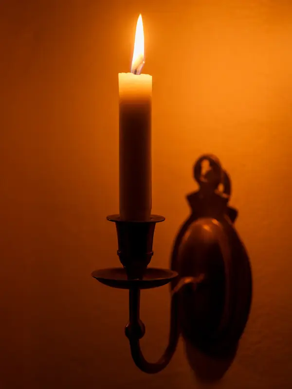 Nærbilde av vegglysestake med tent stearinlys