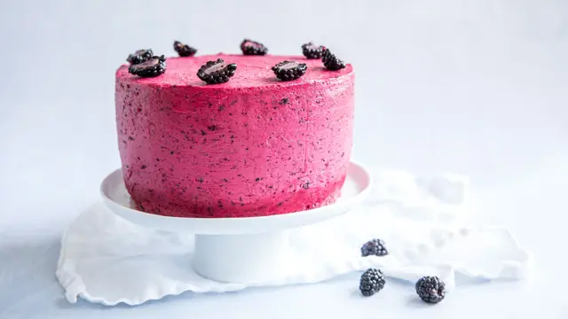 Hvitt fat med en kake med skogsbærkrem