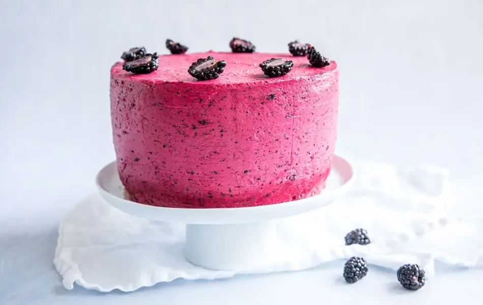 Hvitt fat med en kake med skogsbærkrem