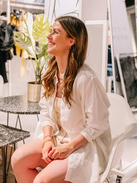 Dame som sitter og smiler i shorts og linskjorte