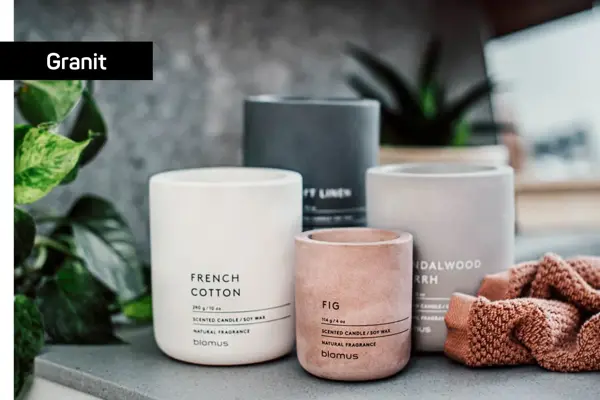 Grått, hvitt, sort og ferskenfarget duftlys som står på et bord