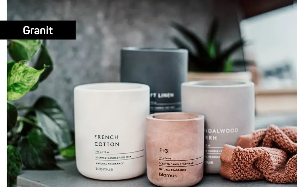 Grått, hvitt, sort og ferskenfarget duftlys som står på et bord