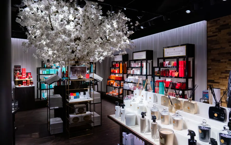 innsiden av butikken med et  hvitt stort tre i midten av rommet med velvære produkter rundt