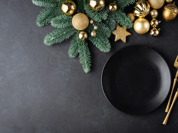 Christmas or New Year table setting background with black plate and golden color cutlery. Top view with copy space for text, design elements, graphics