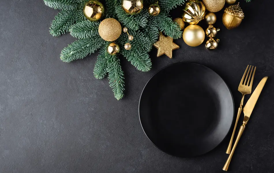 Christmas or New Year table setting background with black plate and golden color cutlery. Top view with copy space for text, design elements, graphics