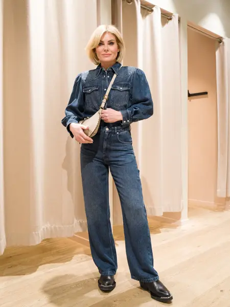 Dame i jeansskjorte, jeans, sorte sko og en lys veske