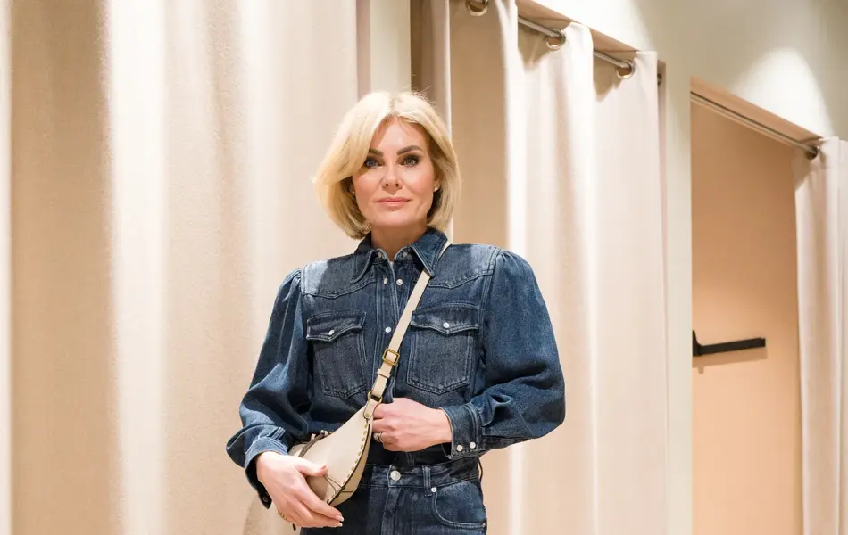 Dame i jeansskjorte, jeans, sorte sko og en lys veske