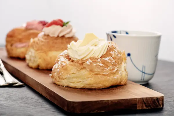 Fastelavnboller or Fastelavn Buns are a Danish delicacy made and eaten in great quantities in the period up to the beginning of Lent in many parts of Scandinavia. Made from puff pastry and filled with cream and or jam and topped with a variety of different flavours, fruits, chocolate and icing . Colour, horizontal with copy space.