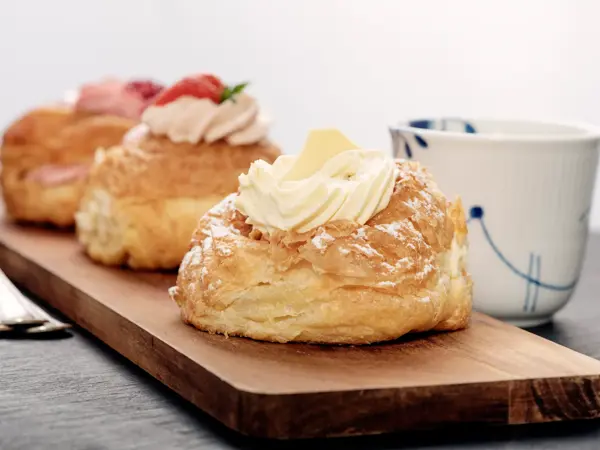 Fastelavnboller or Fastelavn Buns are a Danish delicacy made and eaten in great quantities in the period up to the beginning of Lent in many parts of Scandinavia. Made from puff pastry and filled with cream and or jam and topped with a variety of different flavours, fruits, chocolate and icing . Colour, horizontal with copy space.