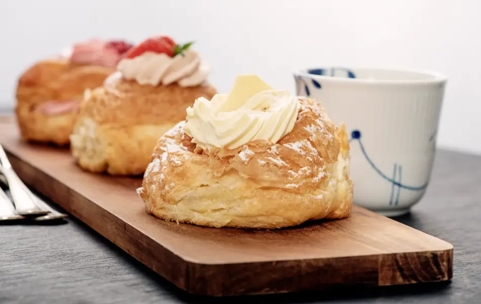 Fastelavnboller or Fastelavn Buns are a Danish delicacy made and eaten in great quantities in the period up to the beginning of Lent in many parts of Scandinavia. Made from puff pastry and filled with cream and or jam and topped with a variety of different flavours, fruits, chocolate and icing . Colour, horizontal with copy space.