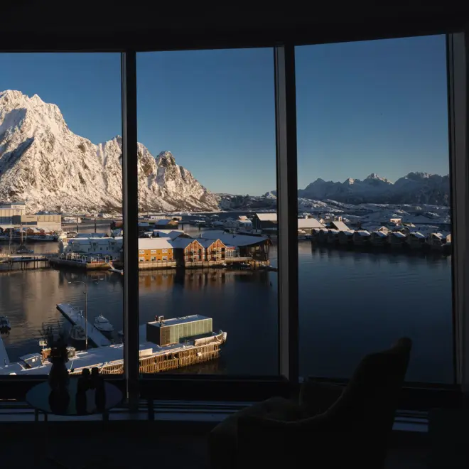 Utsikt fra hotellrom over vannet, byen og snødekte fjell i bakgrunnen