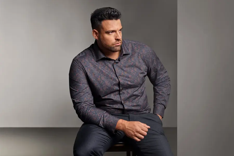 Mann i mønstrete skjorte sitter på stol