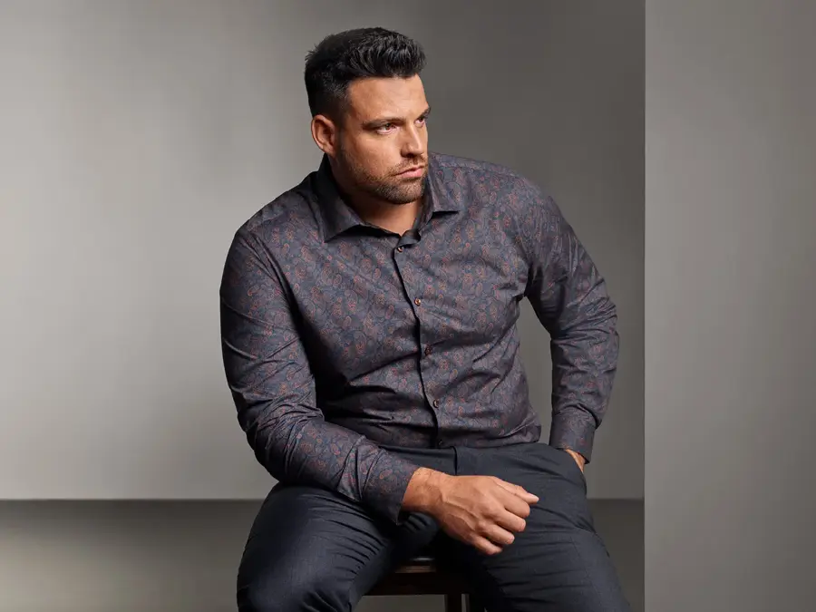 Mann i mønstrete skjorte sitter på stol