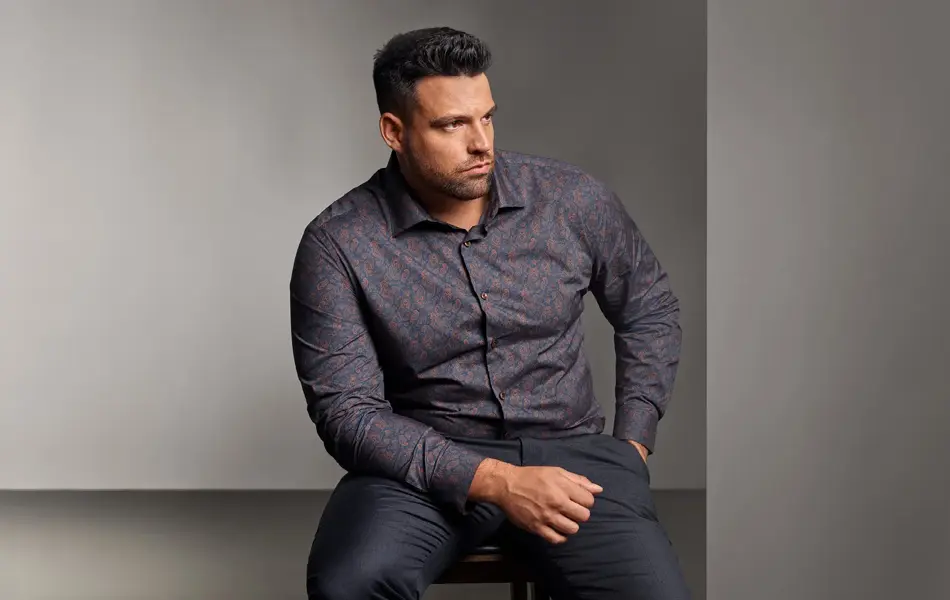 Mann i mønstrete skjorte sitter på stol