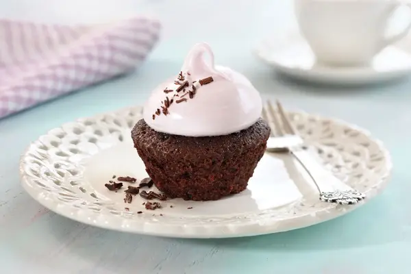 En sjokolademuffins med rosa topping på et hvitt fat