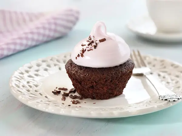 En sjokolademuffins med rosa topping på et hvitt fat