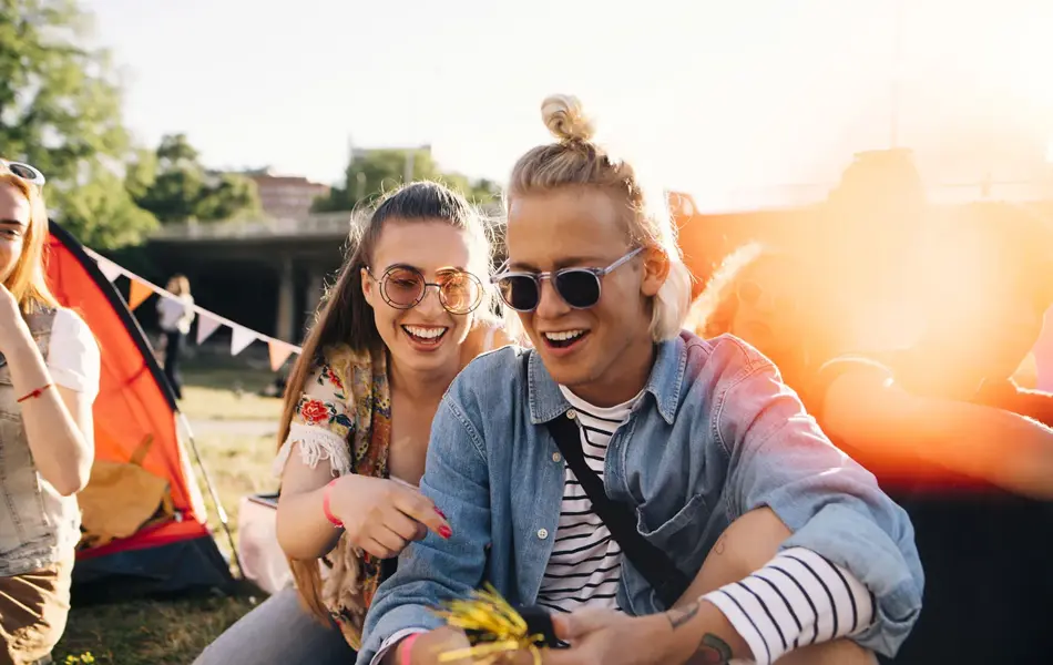 En ung mann og en dame sitter på bakken. Begge smiler.