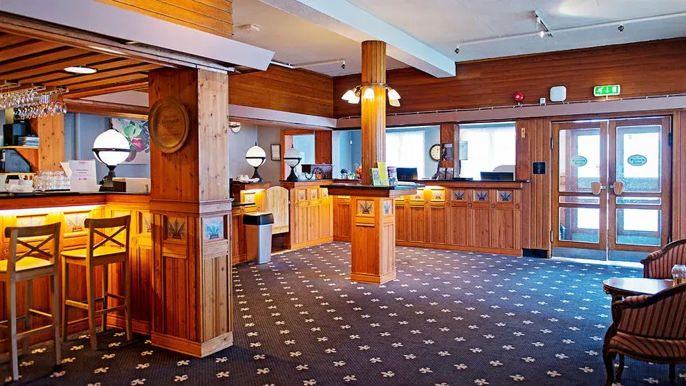 Resepsjonsdisk i treverk til venstre, inngangsdør til høyre. 