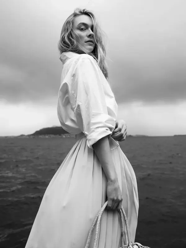 Ung jente poserer foran kamera med havet i bakgrunnen