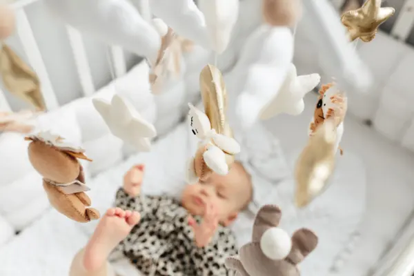 Little baby girl sleeps on a bed in a green suit, playmobile revolves over her.