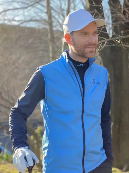 Mann smiler og holder i en golfkølle