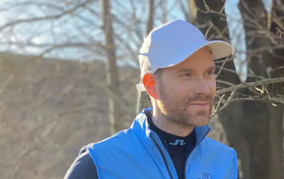 Mann smiler og holder i en golfkølle