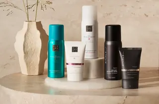 Rituals deodoranter i spray- og kremformat plassert på et bord ved en vase.