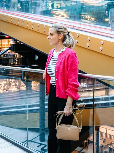 dame i vårklær står utenfor butikk