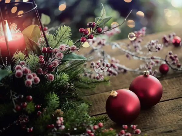Christmas lantern and holiday baubles in red, festive and sparkling lights on a wood surface.