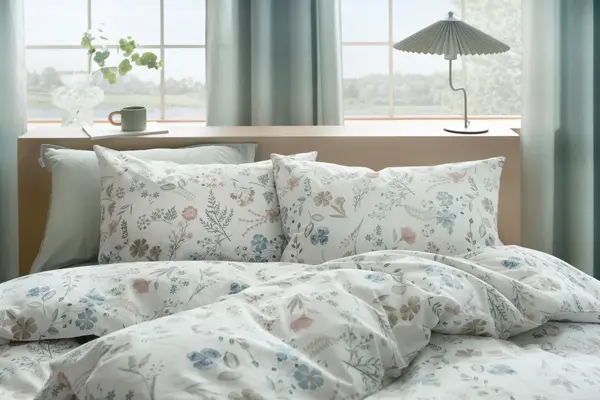 Seng med blomstrete sengetøy.